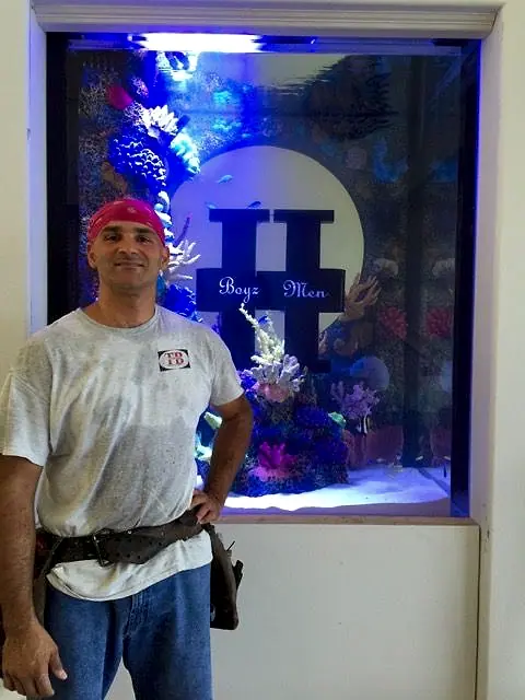 Crew member beside a finished in-wall aquarium