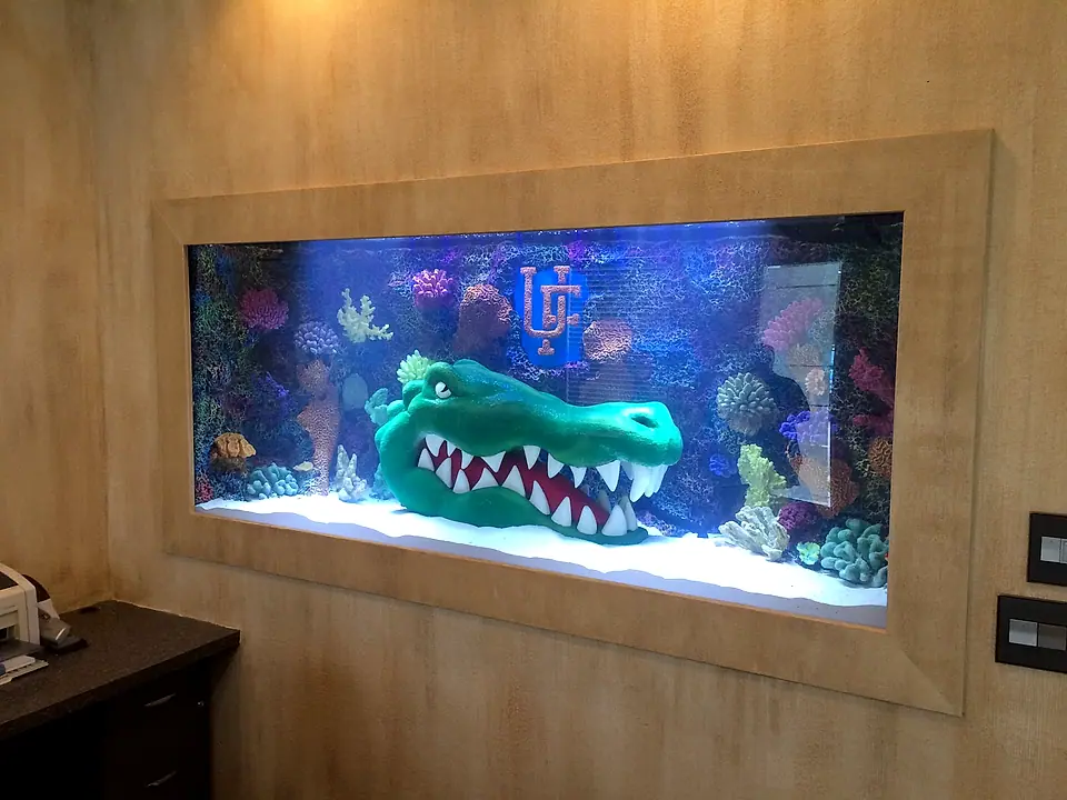 Custom in-wall aquarium framed into a wood-paneled office wall