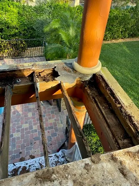 Rotted balcony framing exposed under the old pavers