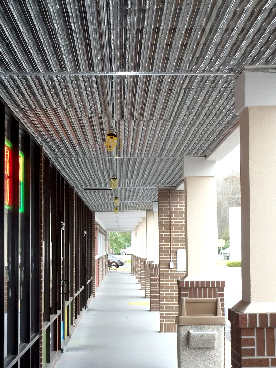 Storefront walkway with new metal ceiling and brick column bases