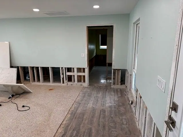 Hallway and room with the lower drywall removed after water damage