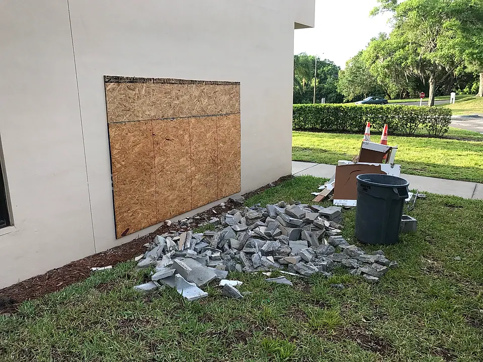 Damaged wall boarded up with debris staged for removal