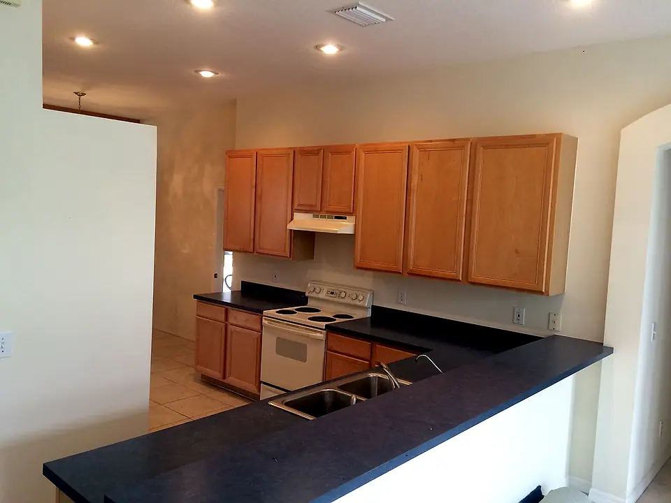Remodeled kitchen with honey oak cabinets, dark counters and a peninsula bar