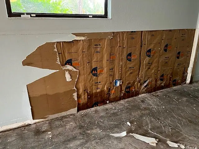 Water-damaged ceiling drywall pulled down to expose the insulation