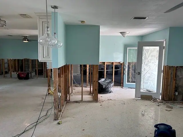 Flood-damaged walls opened to the studs with drying equipment running