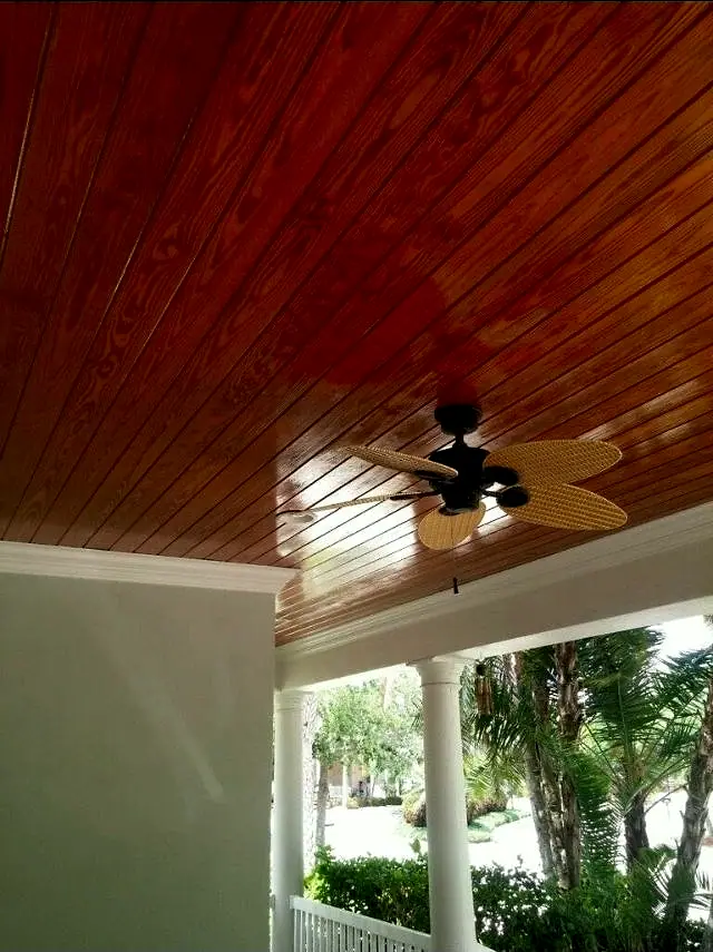 Stained wood porch ceiling with a ceiling fan