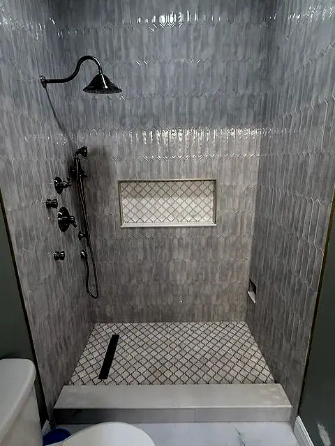 Shower with stacked linear tile, a recessed niche and a marble bench