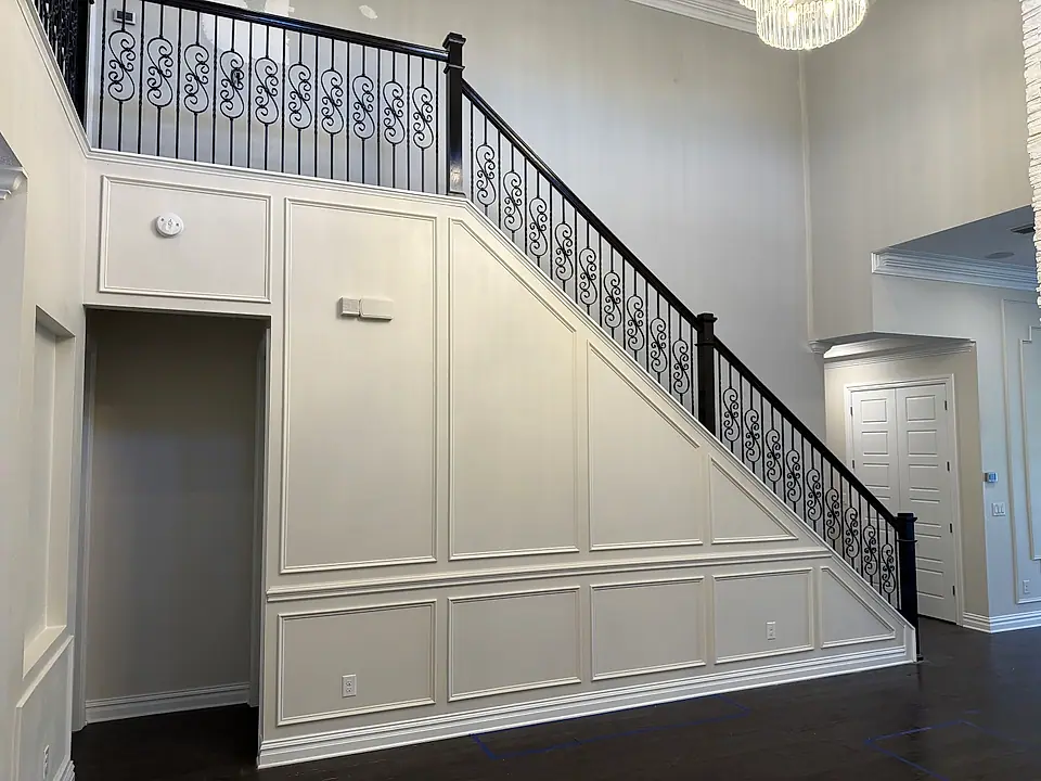 Staircase with wainscoting panels and wrought-iron balusters