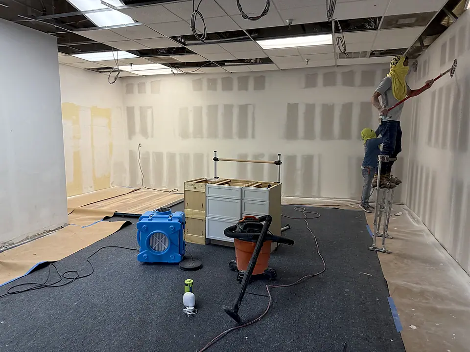 Commercial studio after water damage, drywall patched with air movers running