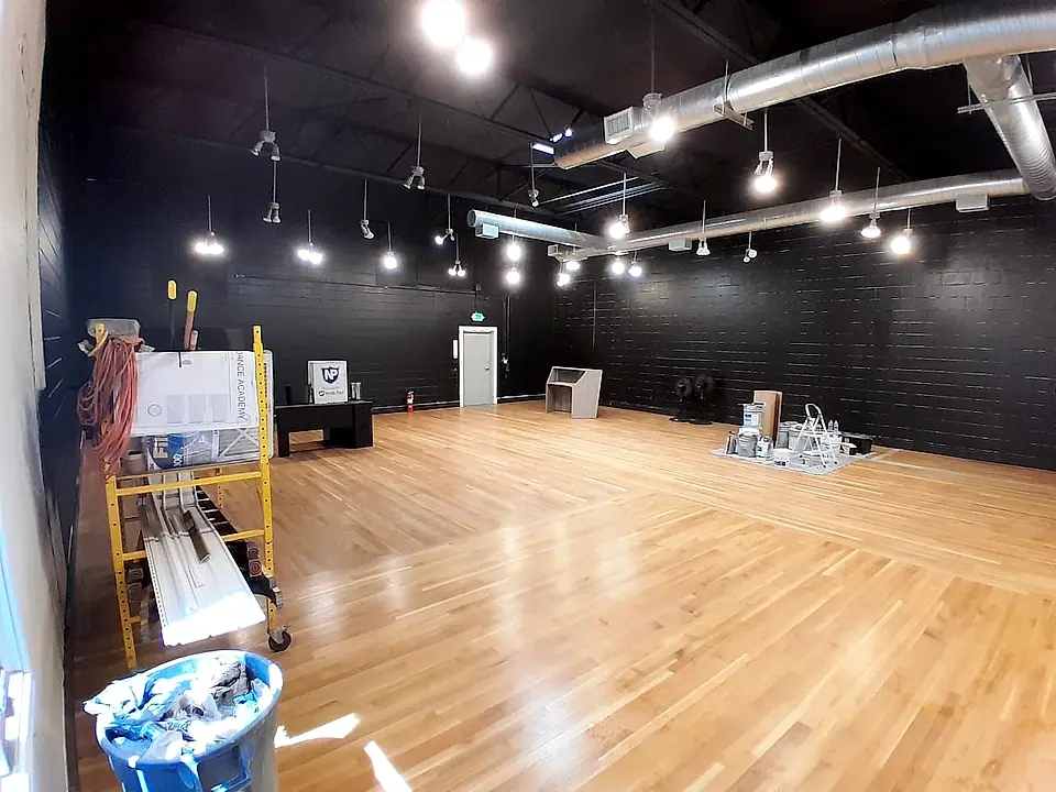 Hardwood floor finished in a studio with black walls and track lighting