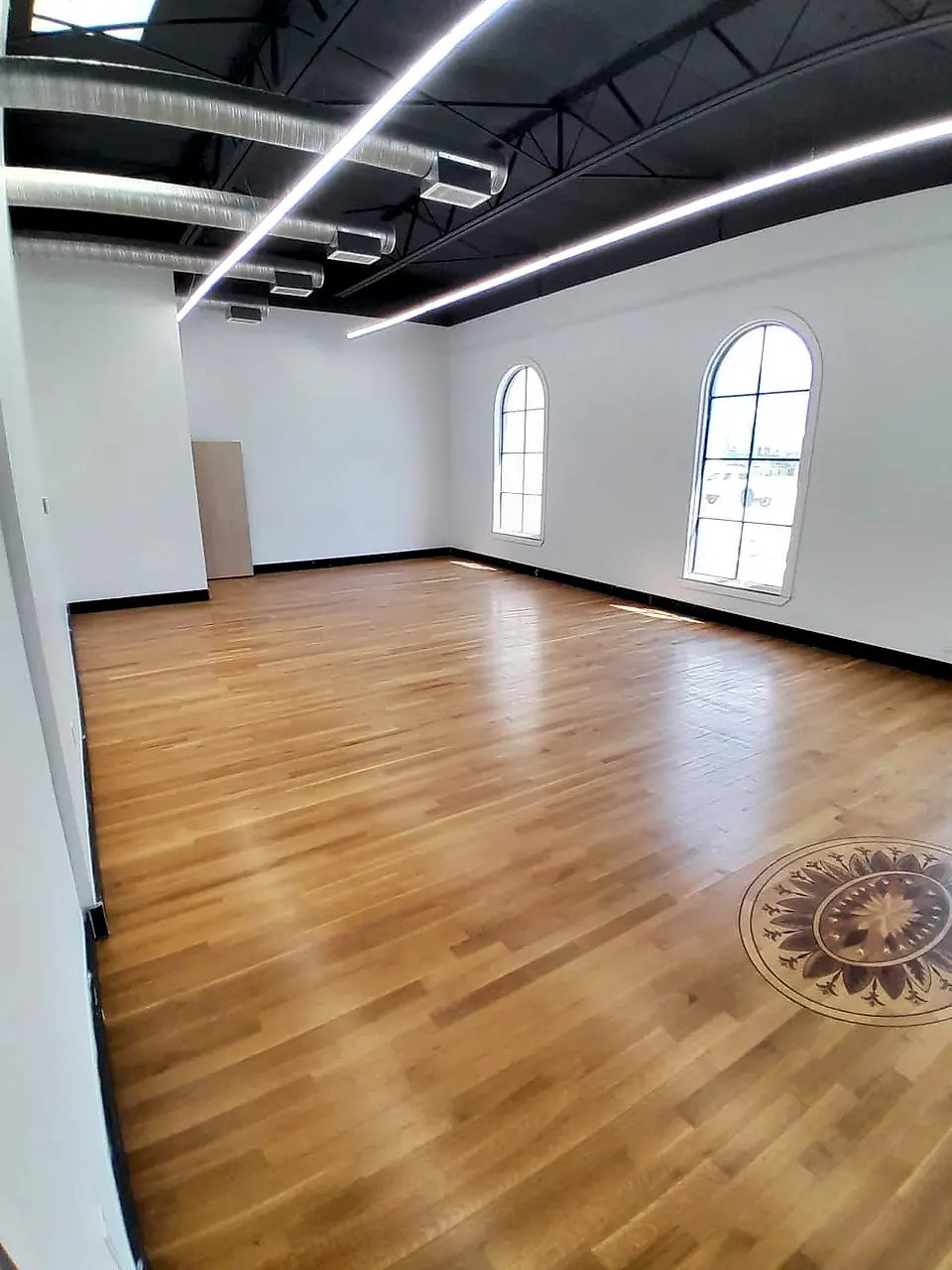 Hardwood floor with an inlaid medallion under arched windows