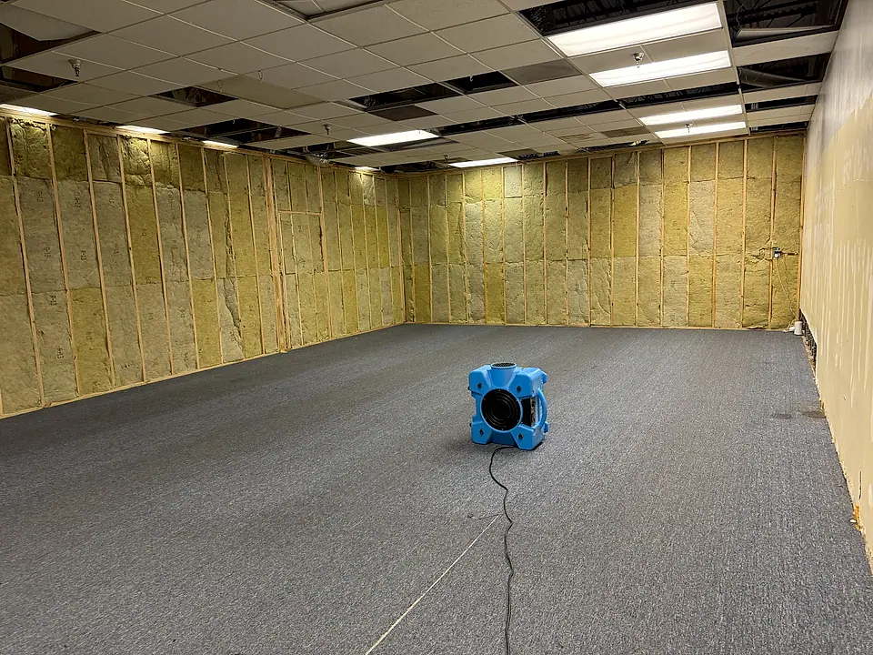 Air mover drying a gutted commercial space after water damage